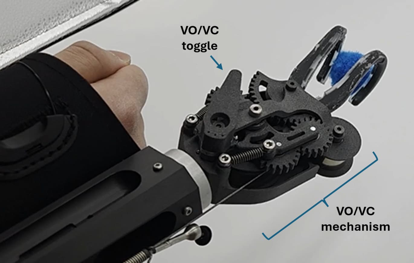 a prosthetic split-hook connected to a socket. an able-bodied manipulator is wearing the socket and is grasping a fluffy blue thing